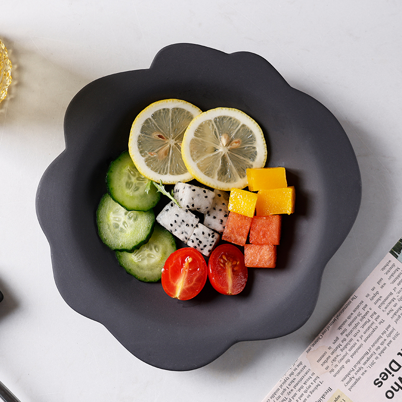 Black ceramic serving plate with a scalloped rim
